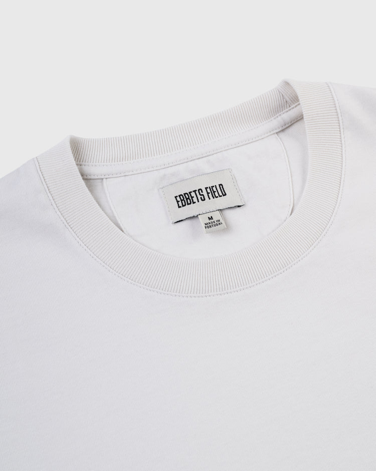 Close-up of a white Los Angeles Angels (PCL) Embroidered ‘LA’ Short Sleeve Tee by Ebbets Field, with visible collar label stating medium size and made in Korea, featuring subtle 1942 LA team logo details on a light background.