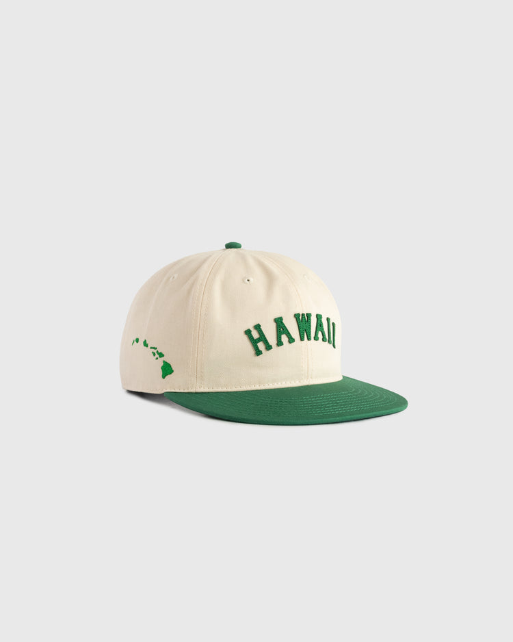 The Ebbets Field Hawaii Islanders (PCL) Cotton Twill Ballcap features a cream body, green brim, “HAWAII” embroidered in green on the front, and a stitched green Hawaiian islands outline on the side. Shown against a plain gray background.