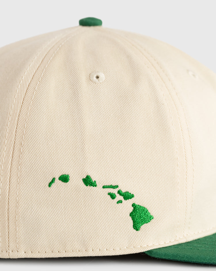 Close-up of Ebbets Fields Hawaii Islanders (PCL) cotton twill ballcap in beige with a green brim. The front features a stitched green outline of the Hawaiian Islands, ideal for fans of classic Hawaii Islanders hats.