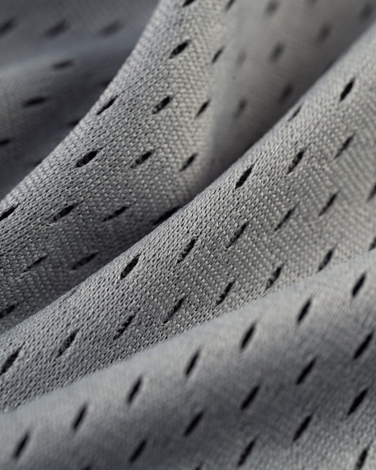 Close-up of light gray mesh fabric with small diamond-shaped holes and gentle folds, like the breathable material on the Ebbets Field Puerto Rico 1958 National Team Mesh V-Neck Jersey.