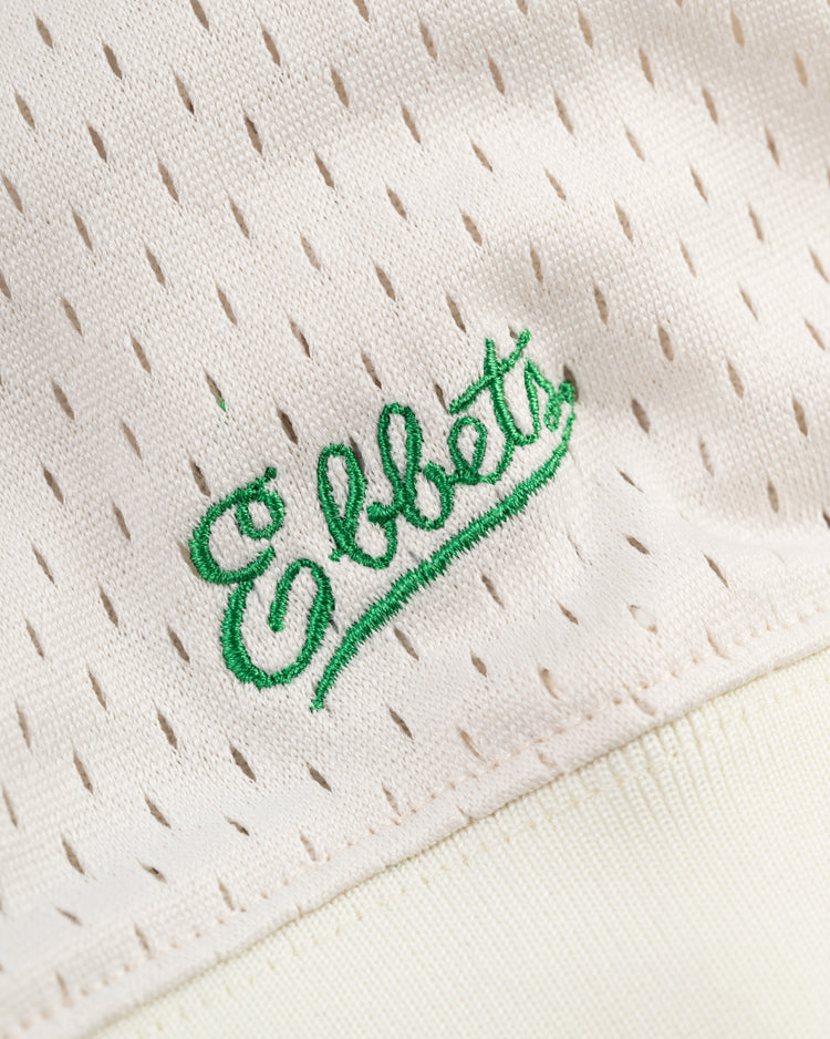 Close-up of the cream Hawaii Islanders (PCL) Mesh V-Neck Jersey by Ebbets Field, featuring green Ebbets cursive embroidery and perforated fabric reminiscent of a vintage baseball throwback.