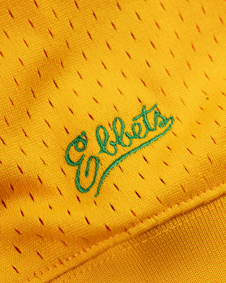 Close-up of yellow mesh fabric with small holes on the Hawaii Islanders (PCL) Mesh V-Neck Jersey by Ebbets Field, showcasing Ebbets embroidered in teal blue script—a detail that captures the vintage, throwback baseball style.