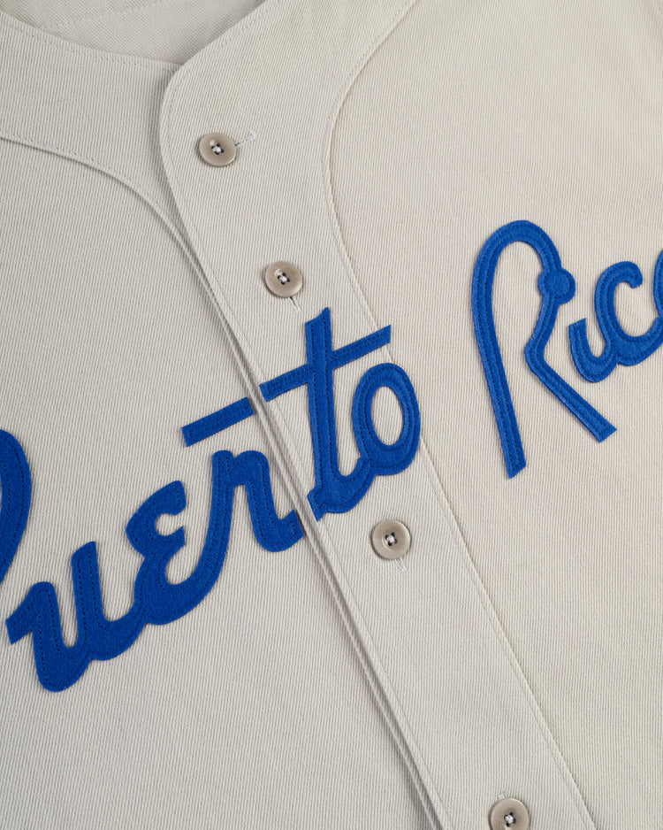 Close-up of Ebbets Field’s Puerto Rico 1958 National Team Cotton Twill Baseball Jersey, featuring cream fabric, blue Puerto Rico script across the front, metallic center buttons, and inspired by the classic 1958 team.