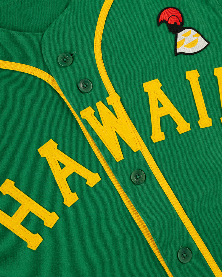 Close-up of the Ebbets Field Hawaii Islanders (PCL) Cotton Twill Baseball Jersey: green with yellow trim and “HAWAII” in yellow letters, plus a red, yellow, and white patch above the “I”—classic Pacific Coast League style.