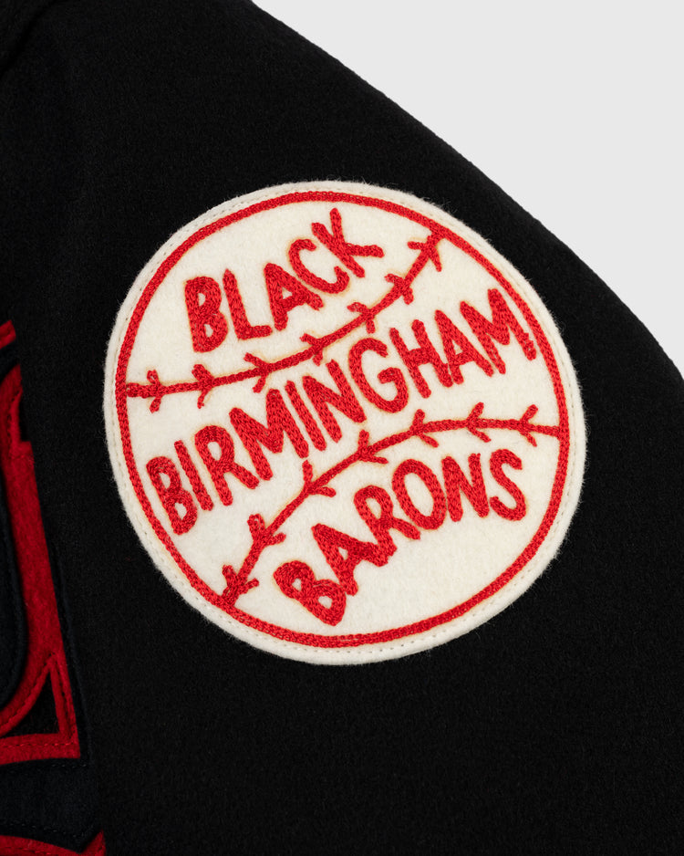 A white circular patch with red baseball stitching and BLACK BIRMINGHAM BARONS in red is sewn onto black fabric—ideal for the EFF Birmingham Black Barons 1940 Authentic All Wool Varsity Jacket.