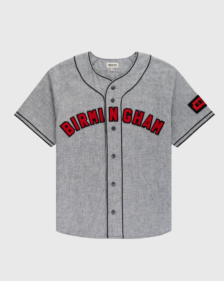 The Ebbets Field Birmingham Black Barons 1948 Authentic Wool Road Jersey is gray with black piping, BIRMINGHAM in bold red/black across the chest, and a red 1921 patch on the left sleeve honoring Negro Leagues Baseball Museum history.