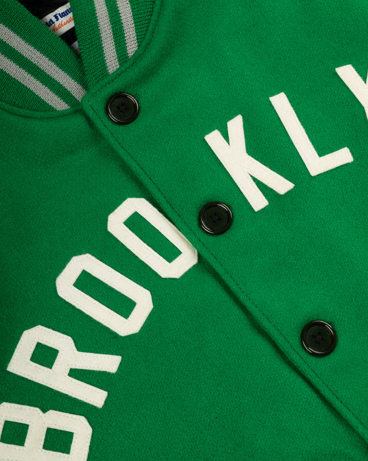 Close-up of the EFF Brooklyn Dodgers 1937 Authentic All Wool Varsity Jacket, green with BROOKLYN in white block letters, black buttons, and a gray-white striped collar, inspired by the classic look at Ebbets Field.