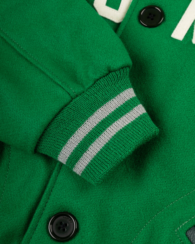 Close-up of an EFF Brooklyn Dodgers 1937 Authentic All Wool Varsity Jacket sleeve with a green ribbed cuff and two light gray stripes. Black buttons and white lettering hint at classic Ebbets Field memorabilia style.