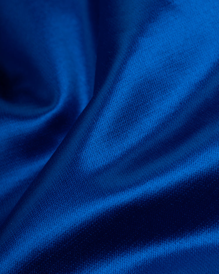 Close-up of smooth, shiny royal blue fabric with soft folds and gentle reflections, evoking the classic EFF Brooklyn Dodgers 1945 Satin Windbreaker Jacket.