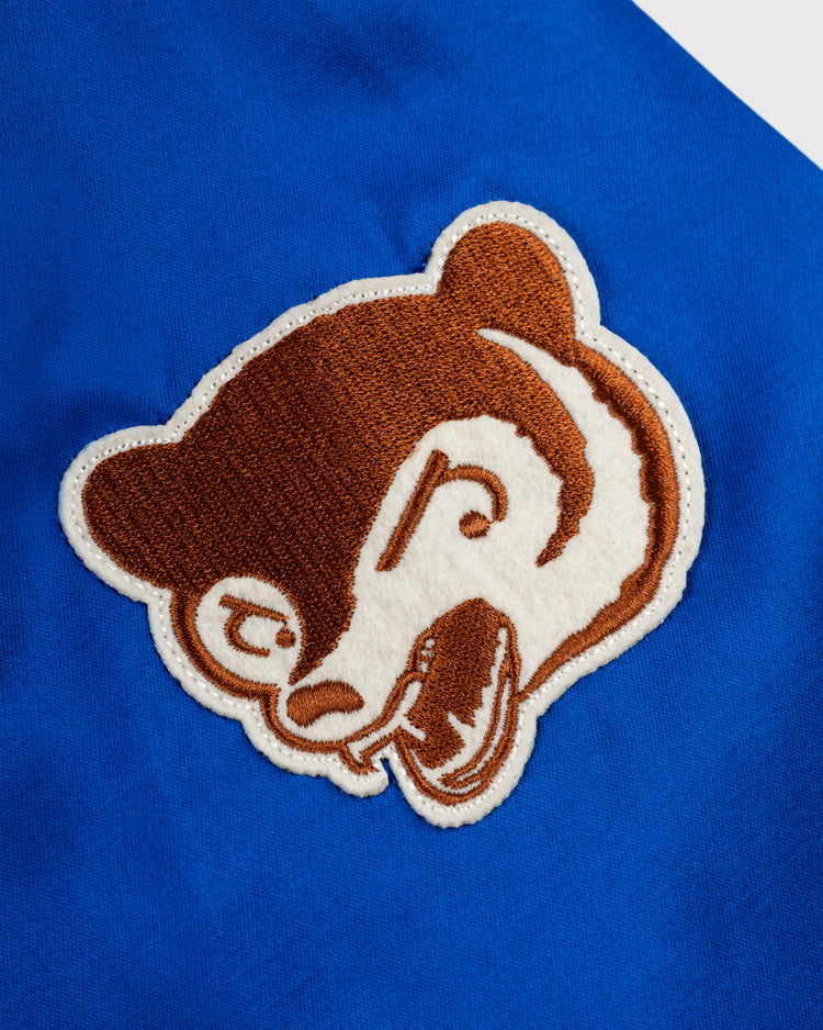 A close-up of a brown and white bear head patch on bright blue fabric from the EFF Chicago Cubs 1946 Satin Windbreaker Jacket, inspired by vintage baseball style.