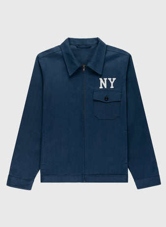 The Ebbets Field Cotton Grounds Crew Jacket by Ebbets Field Flannels is a navy blue cotton jacket with a zip front, pointed collar, buttoned chest pocket, and white NY lettering—ideal for classic spring style.