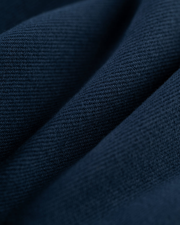 Close-up of the Ebbets Field Flannels Ebbets Cotton Linen Grounds Crew Short Sleeve Workshirt fabric in dark blue, highlighting its visible texture and weave in gentle folds.