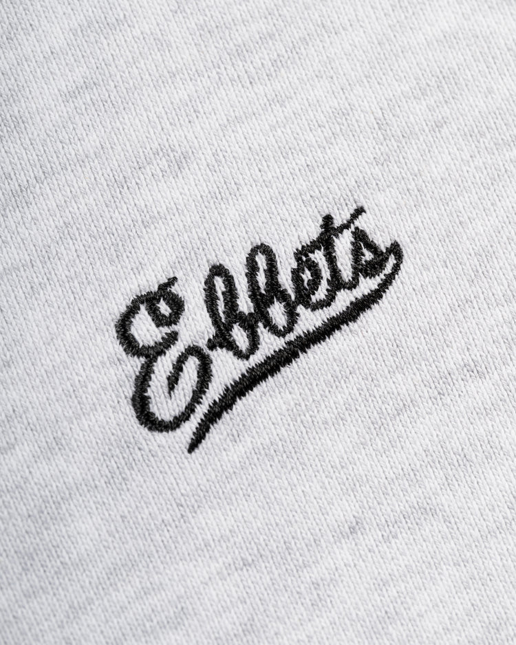 Close-up of the Ebbets Chest Logo Heavyweight Cotton Terry Crewneck by Ebbets Field Flannels, featuring Effets embroidered in black, cursive lettering on white cotton for a vintage-inspired look.
