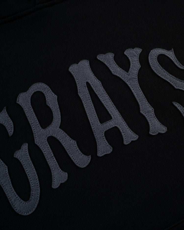 Close-up of dark gray, textured GRAYS lettering on black cotton terry—classic details that give the Ebbets Field Flannels Homestead Grays Heavyweight Pullover Hoodie its timeless appeal.