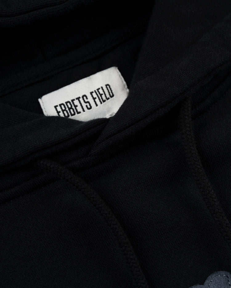 Close-up of the Homestead Grays Heavyweight Cotton Terry Pullover Hoodie by Ebbets Field Flannels, featuring a white collar label with bold black EBBETS FIELD text, plus visible drawstrings and stitching inspired by the Grays.