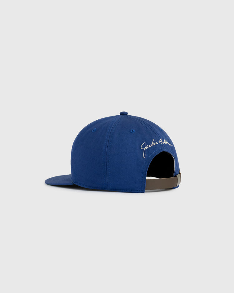 The Ebbets Field Jackie Robinson Day Montreal Royals ‘M’ Cotton Twill Ballcap features a vintage design, brown adjustable strap, and white cursive Jackie Robinson text above the back opening.