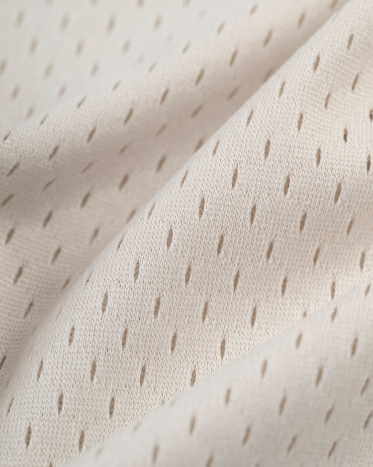 Close-up of the Ebbets Field Jackie Robinson Mesh V-Neck Jerseys light beige fabric, featuring evenly spaced diagonal perforations for a soft, retro-inspired look with gentle folds.