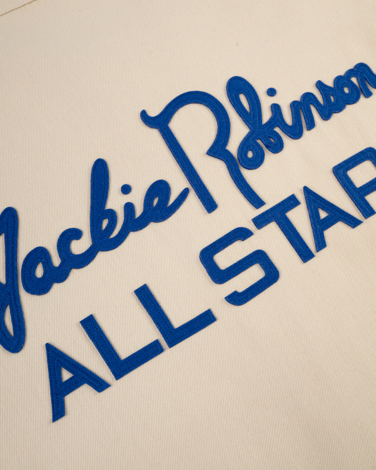 Close-up of blue cursive and block lettering on cream cotton twill fabric reading “Jackie Robinson ALL STAR,” from the Ebbets Field Jackie Robinson Cotton Twill Baseball Jersey.