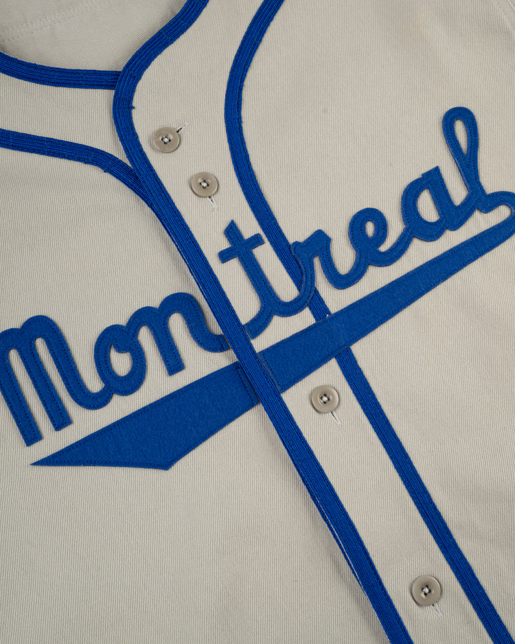 Close-up of the Ebbets Field Montreal Royals Cotton Twill Baseball Jersey, featuring blue trim, buttons, and Montreal in bold blue script across the chest.