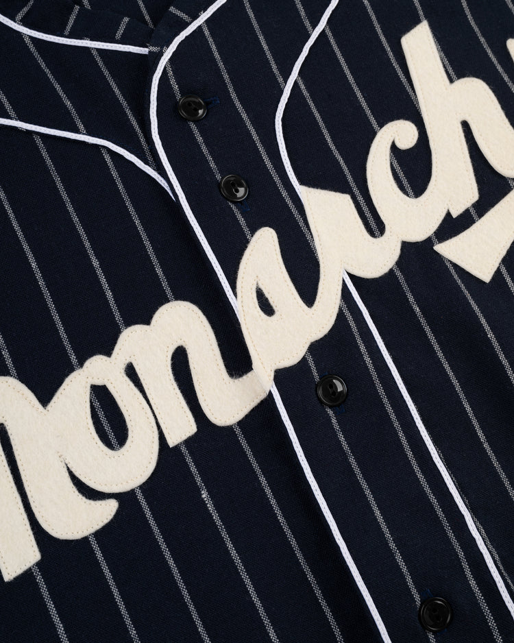 Close-up of the Ebbets Field Kansas City Monarchs 1924 Authentic Wool Road Baseball Jersey, with navy pinstripes, white piping, and cream lettering spelling Monarch across the chest—a classic tribute to Negro Leagues baseball. Black front buttons included.