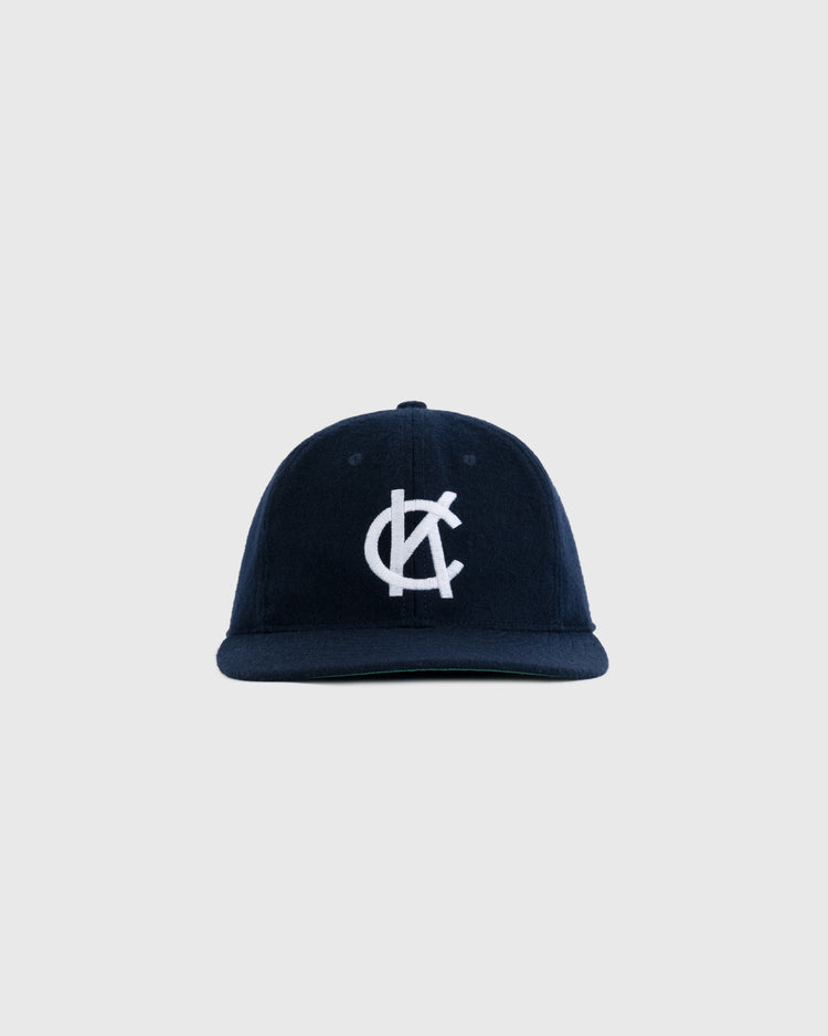 The EFF Kansas City Blues 1947 Authentic Wool Ballcap is a navy vintage cap with a white embroidered interlocking C and K logo on front, inspired by the original, shown against a light gray background.
