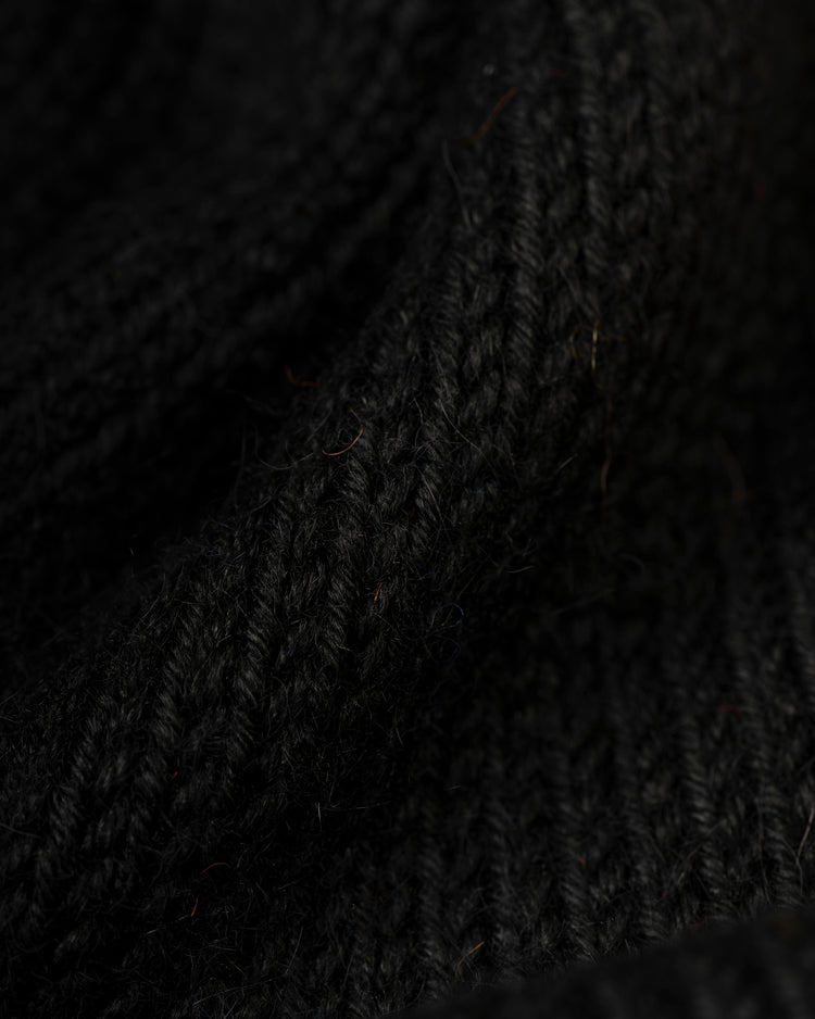 Close-up of black ribbed knit fabric on the Ebbets Field Flannels Baltimore Orioles 1964-65 Wool Shawl Collar Sweater, showing detailed texture, yarn fibers, and soft shadowed folds.