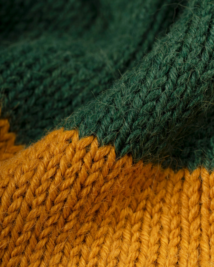 Close-up of Ebbets Field Flannels’ Oakland Athletics 1969 Wool Shawl Collar Sweater, showing thick, soft knit in green and mustard yellow with visible yarn texture and clear stitch patterns, reminiscent of vintage A’s apparel.