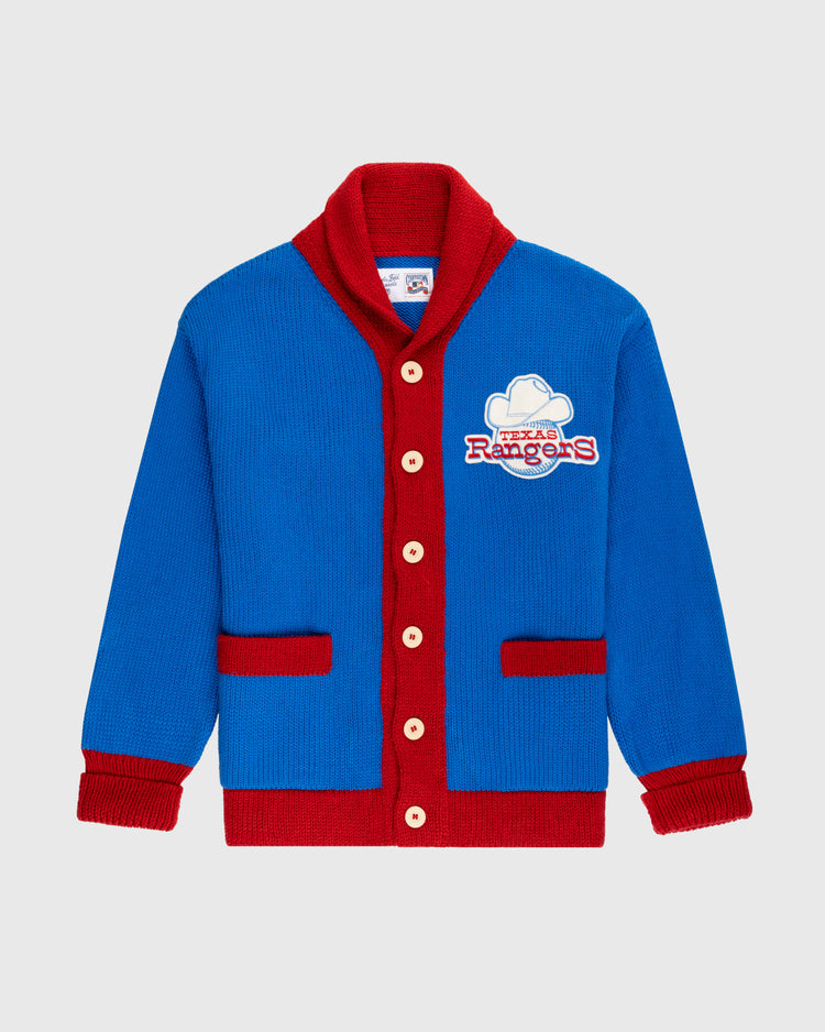 The Ebbets Field Flannels Texas Rangers 1972 Wool Shawl Collar Sweater is a blue knit replica with red trim, buttons, and pockets, plus a Rangers logo patch on the chest—a stylish choice for true MLB fans.