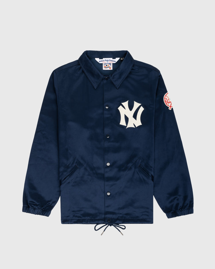 The EFF New York Yankees 1946 Satin Windbreaker Jacket is navy blue with a collar, elastic cuffs, drawstring hem, a large white Yankees logo on the left chest, and a circular Yankees patch on the sleeve.