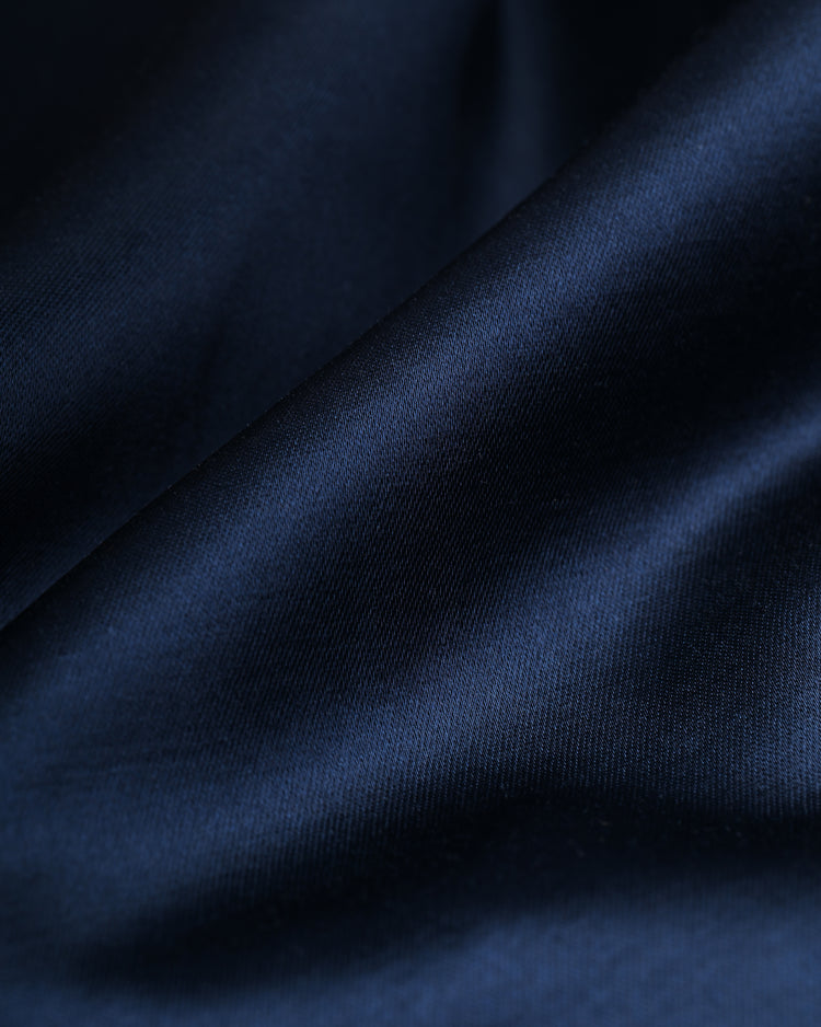 Close-up of smooth, dark blue satin fabric with gentle folds, evoking the vintage style of the EFF Los Angeles Angels 1946 Satin Windbreaker Jacket and highlighting its soft texture and subtle sheen.