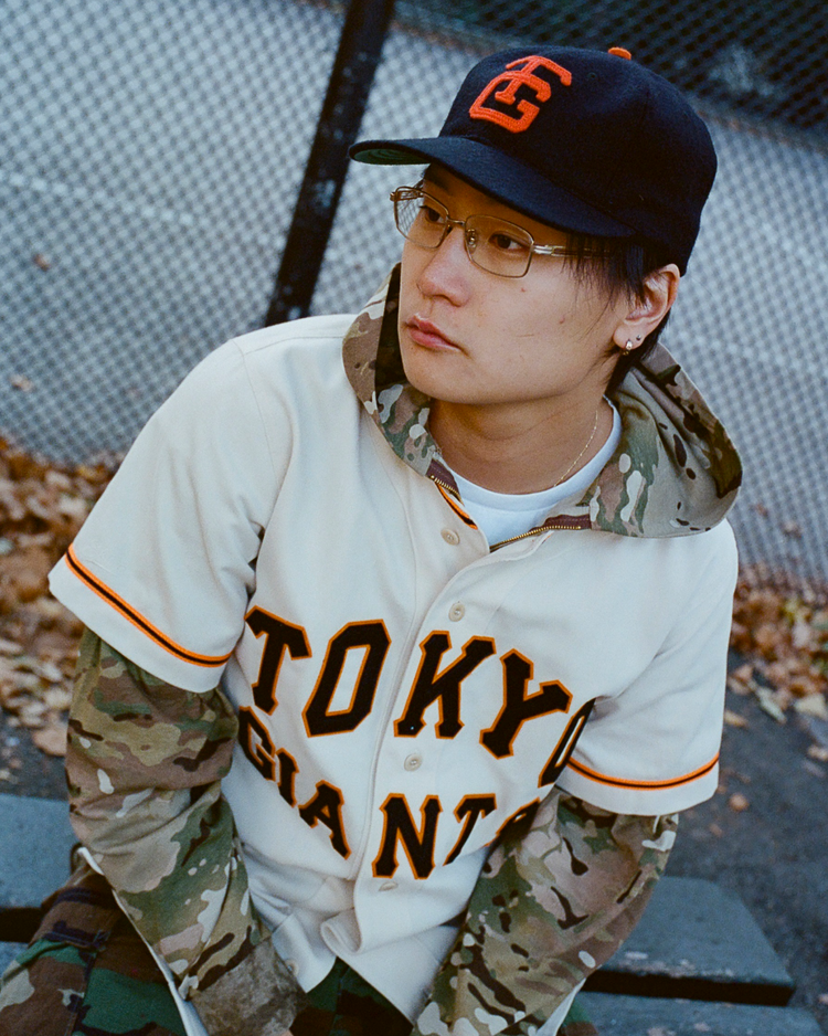 Person wearing a Tokyo Giants jersey and cap with an orange Tokyo Giants logo in an outdoor setting