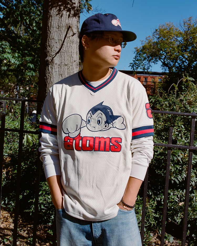 Person wearing a Sankei Atoms mesh jersey with a logo and text, standing outdoors.