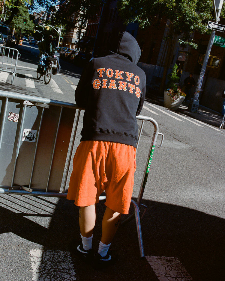 Person wearing a block 'Tokyo Giants' hoodie on a city street