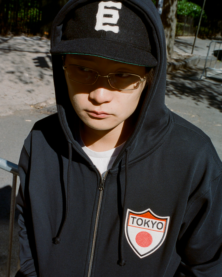 Person wearing a black hoodie with 'TOKYO' logo and a black wool ball cap with the Tokyo Giants logo outdoors.