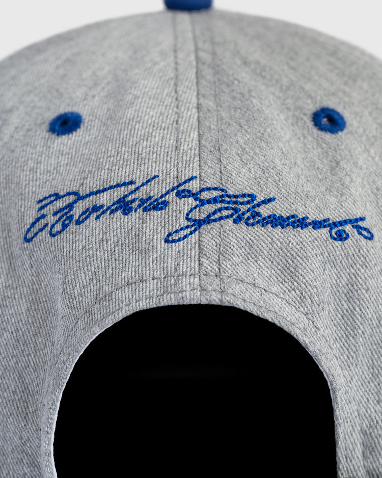 A close-up of the back of a gray Ebbets Field Puerto Rico 1958 National Team Cotton Twill Ballcap with blue embroidered cursive text reading Future Glamour above the opening.