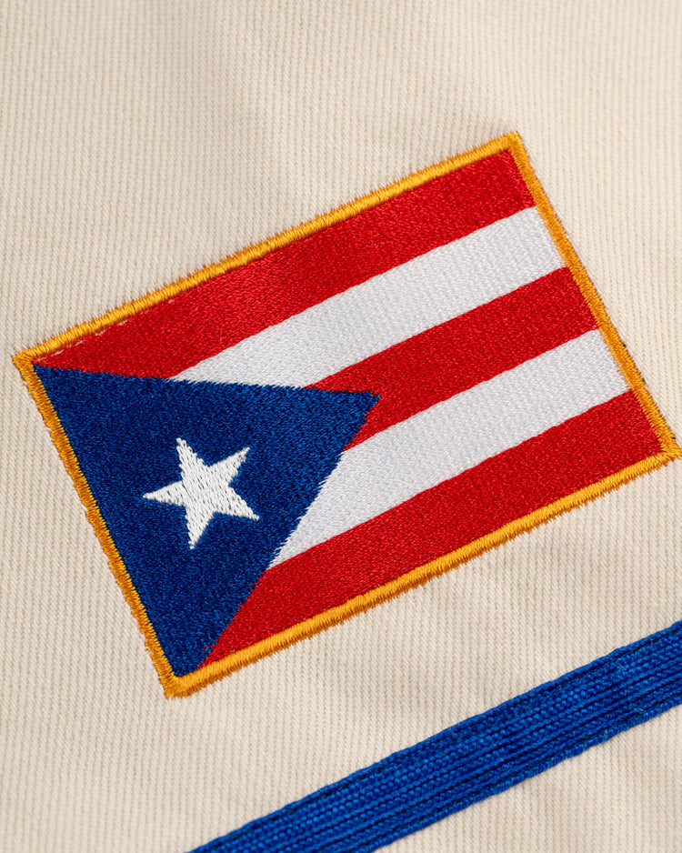Ebbets Field’s Santurce Cangrejeros Cotton Twill Baseball Jersey features a beige embroidered Puerto Rican flag patch with red and white stripes, a blue triangle with white star, and a yellow border, inspired by the iconic team style.