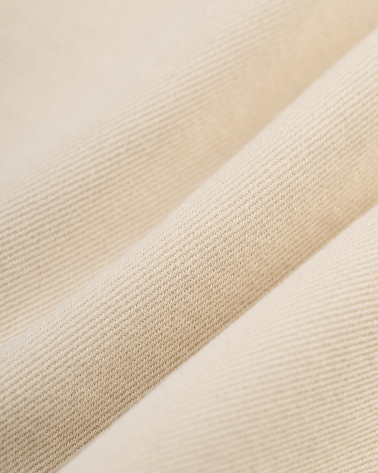 Close-up of the Ebbets Field Santurce Cangrejeros Cotton Twill Baseball Jersey fabric, featuring light beige cotton twill with a textured diagonal ribbed pattern, fine woven threads, and soft folds inspired by classic vintage jerseys.