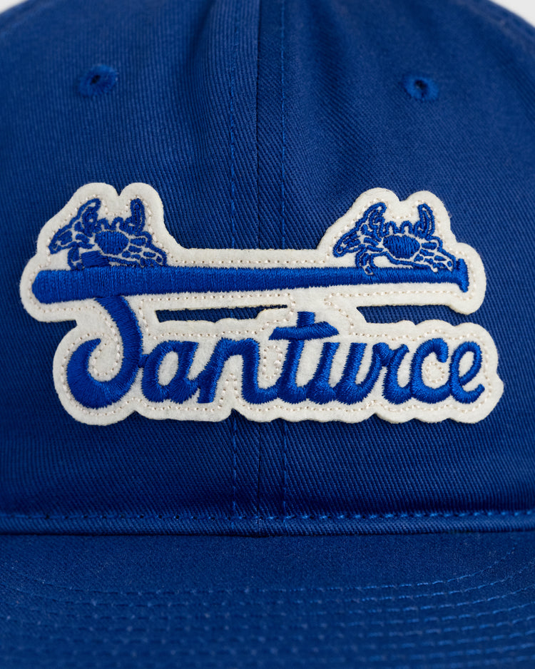 A close-up of the Ebbets Field Santurce Cangrejeros Cotton Twill Ballcap, featuring a blue design with a white and blue embroidered Santurce patch, two crabs above the text, and tributes to Puerto Rican baseball heritage.