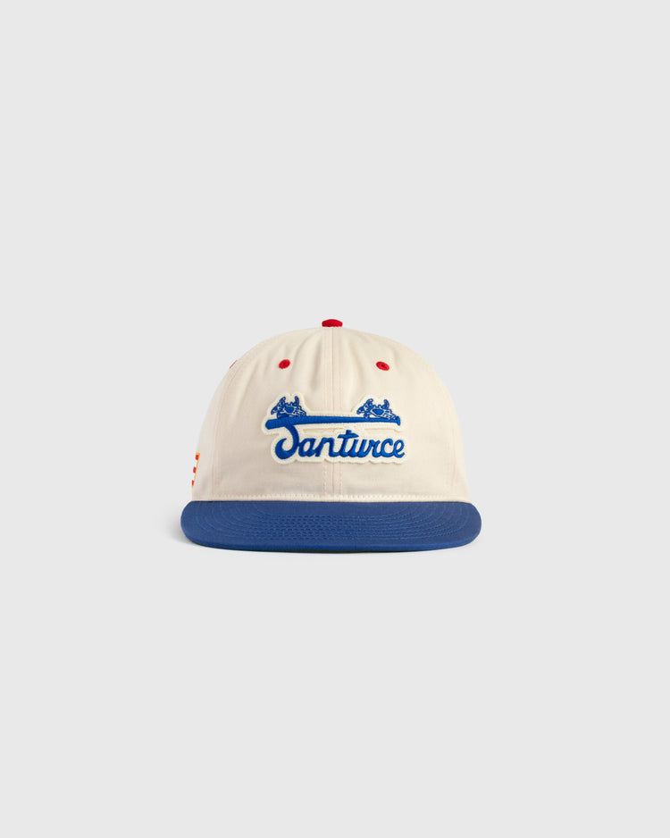 The Ebbets Field Santurce Cangrejeros Cotton Twill Ballcap features a cream crown, blue brim, red accents, Santurce in blue script, and two small blue horses—a classic tribute to Puerto Rican baseball.