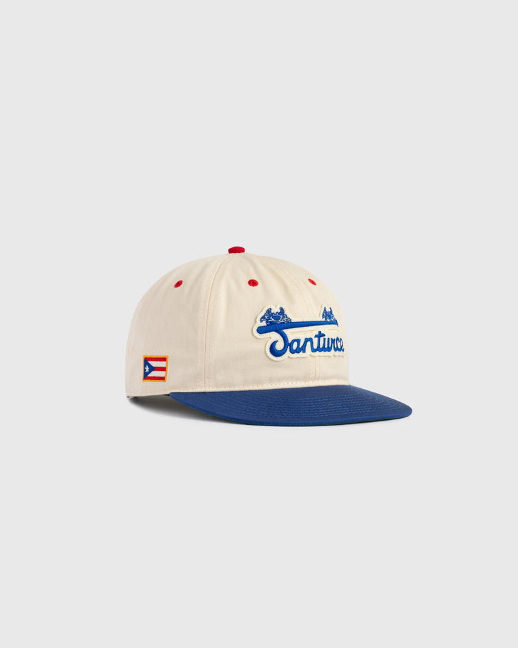The Santurce Cangrejeros Cotton Twill Ballcap by Ebbets Field features a cream crown, blue brim, red accents, Santurce embroidered in blue, and a Puerto Rican flag patch—ideal for fans of Puerto Rican baseball and Roberto Clemente.