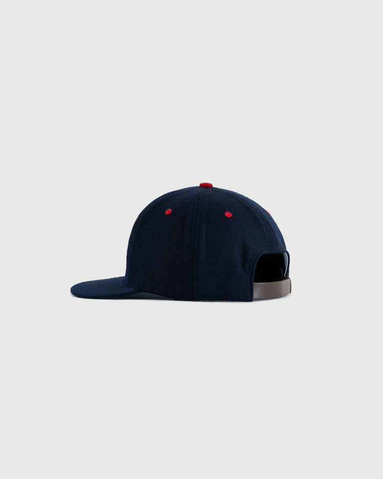 The EFF Seattle Rainiers 1957 Authentic Wool Ballcap is shown from the back, displaying red ventilation eyelets and a grey adjustable strap. This navy blue cap faithfully reproduces the original, set against a plain light gray background.