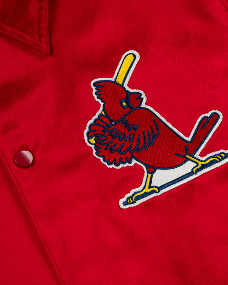 A close-up of the EFF St. Louis Cardinals 1970 Satin Windbreaker Jacket, showcasing an embroidered Cardinals logo with a cardinal on a yellow bat and a red button on the left side of this vintage red MLB outerwear.