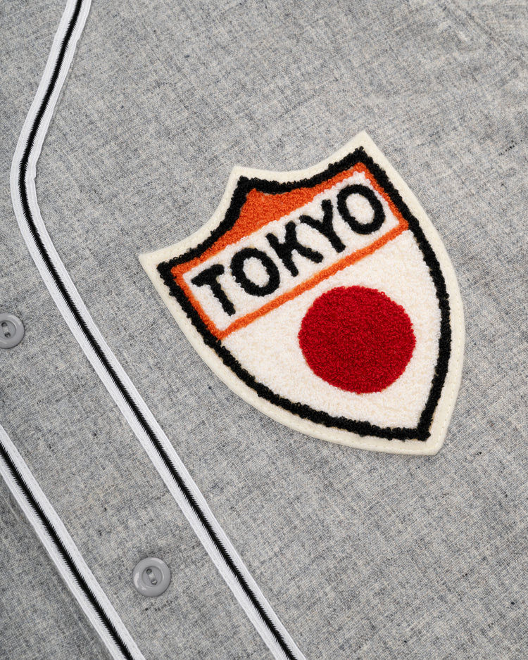 A close-up of the Ebbets Field Flannels Tokyo Kyojin (Giants) 1936 Authentic Wool Road Baseball Jersey, a grey flannel with white piping and a TOKYO patch above a red dot on a shield—reminiscent of the original 1936 design.