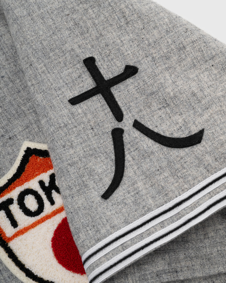 A close-up of the Tokyo Kyojin (Giants) 1936 Authentic Wool Road Baseball Jersey by Ebbets Field Flannels, featuring gray flannel, black kanji, a bold TOKYO patch, and classic black-and-white striped edging.