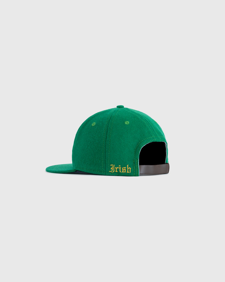 A green EFF University of Notre Dame ND Authentic Wool Ballcap is shown from the back with an adjustable black strap and Irish embroidered in yellow on the left side above the opening. The background is plain light gray.
