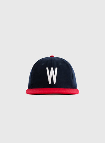 The Wichita Braves 1957 Authentic Wool Ballcap by Ebbets Field Flannels features navy wool, a red brim, and a bold white W on the front, shown against a plain light gray background.