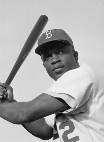 A baseball player wearing a cap with a B logo holds a bat over his shoulder, looking into the distance. The image is in black and white.