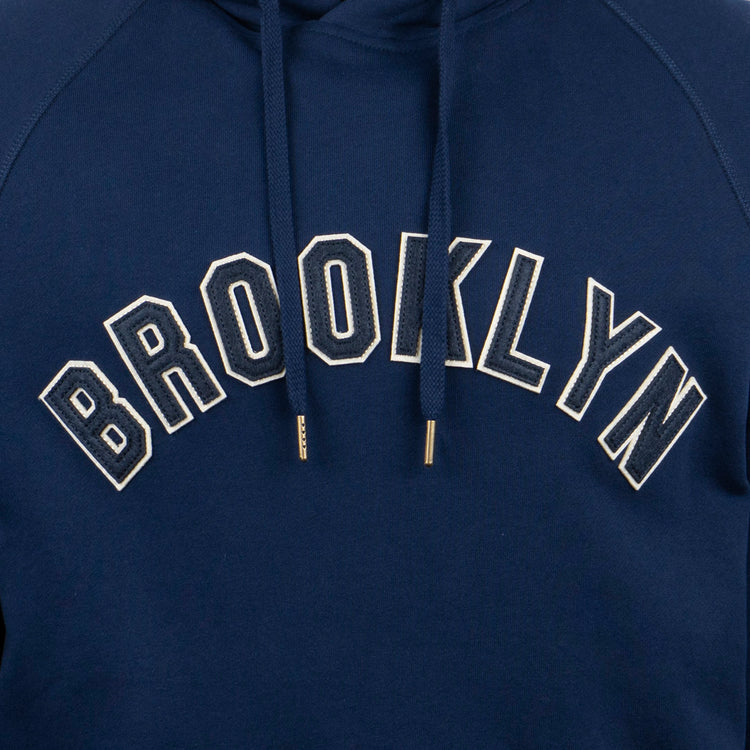 The EFF Brooklyn Eagles French Terry Script Hooded Sweatshirt is navy blue with BROOKLYN in bold white letters on the chest and features metal-tipped drawstrings, paying tribute to the Brooklyn Eagles.