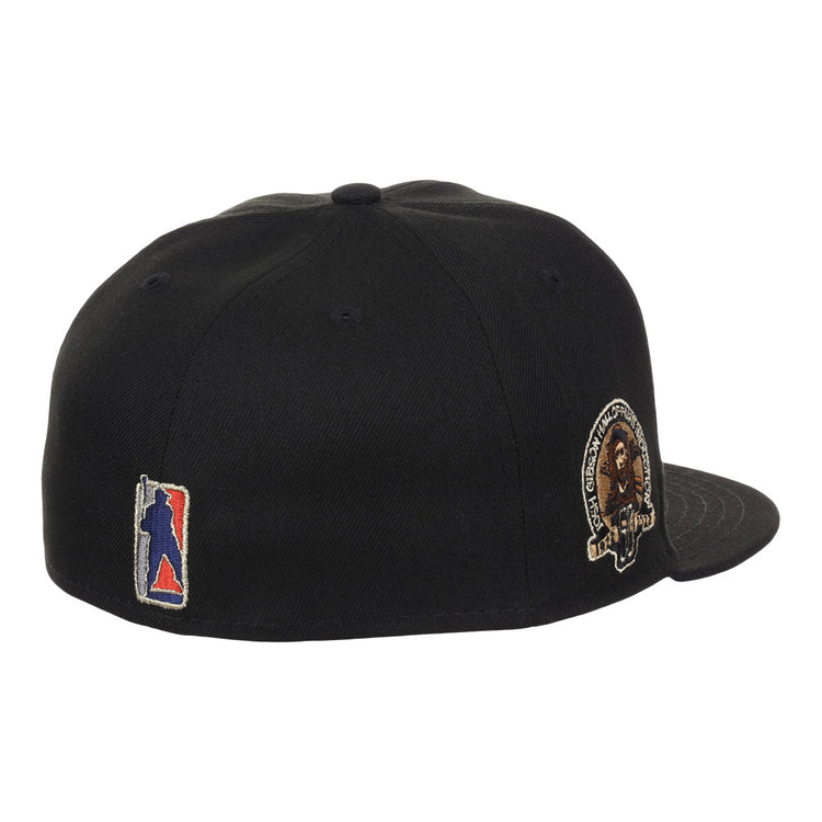 The EFF Homestead Grays Josh Gibson Fitted Ballcap in black is shown from an angled rear view, featuring a multicolor embroidered back logo and a lion patch with text on the left side, inspired by classic Negro Leagues cap designs.