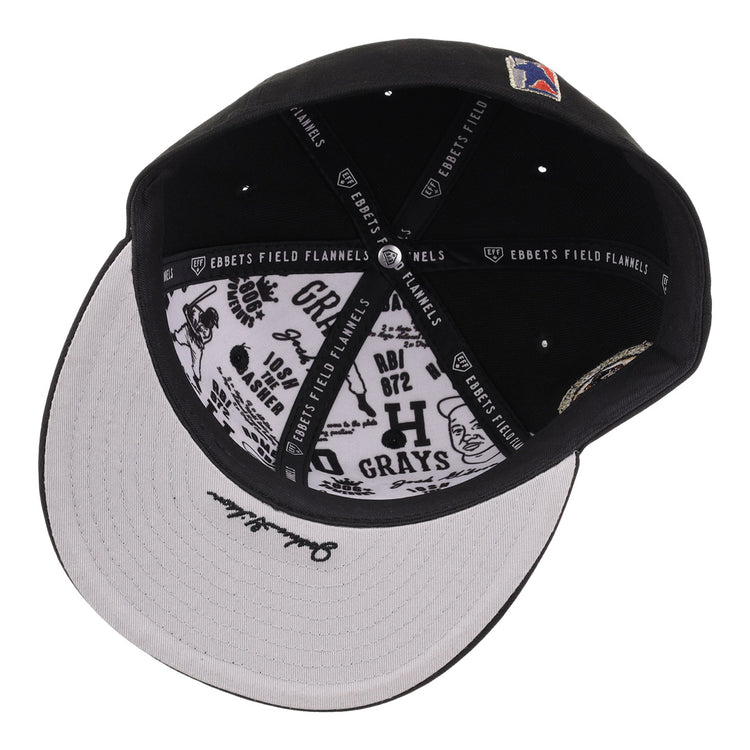 The Homestead Grays Josh Gibson Fitted Ballcap - Black by EFF is shown from above, highlighting its inner lining with EFF branding and black graphic designs and text on the white underside of the brim.